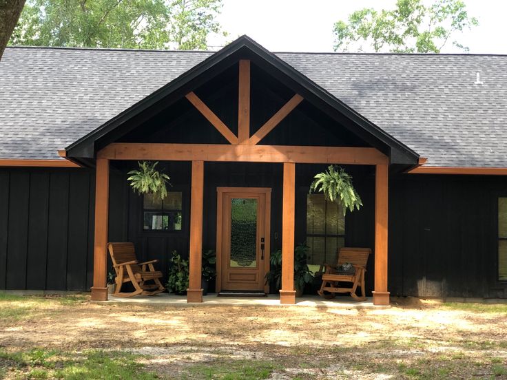 a black house with two rocking chairs on the front porch