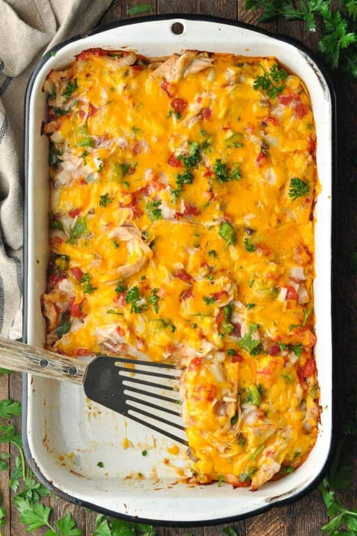 a casserole dish with broccoli, cheese and chicken in it next to a fork