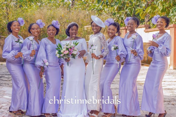 a group of women standing next to each other wearing purple dresses and matching headpieces