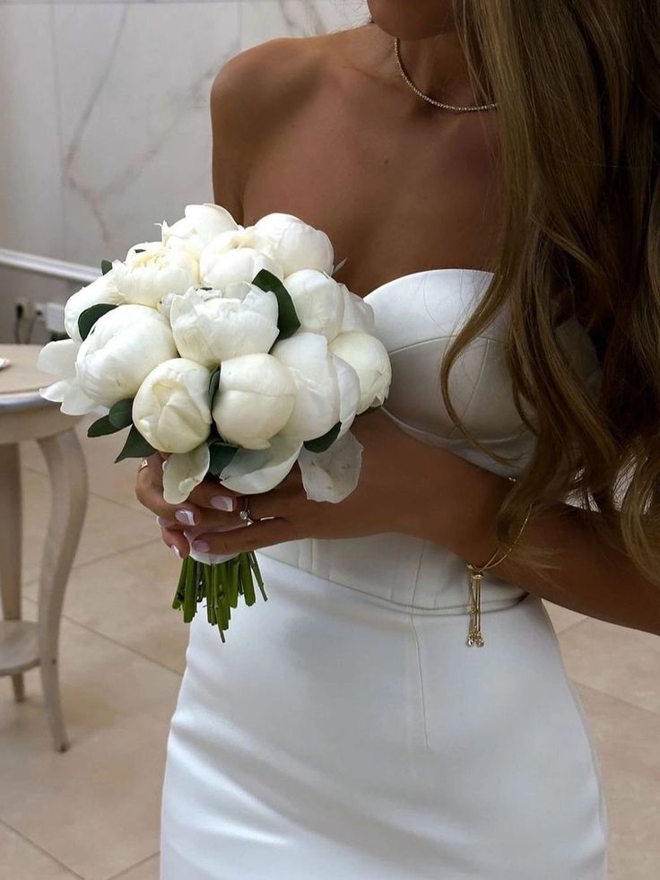 a woman holding a bouquet of white flowers