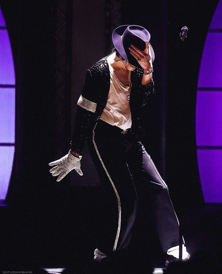 a male in a white shirt and black pants on stage with his hands to his face