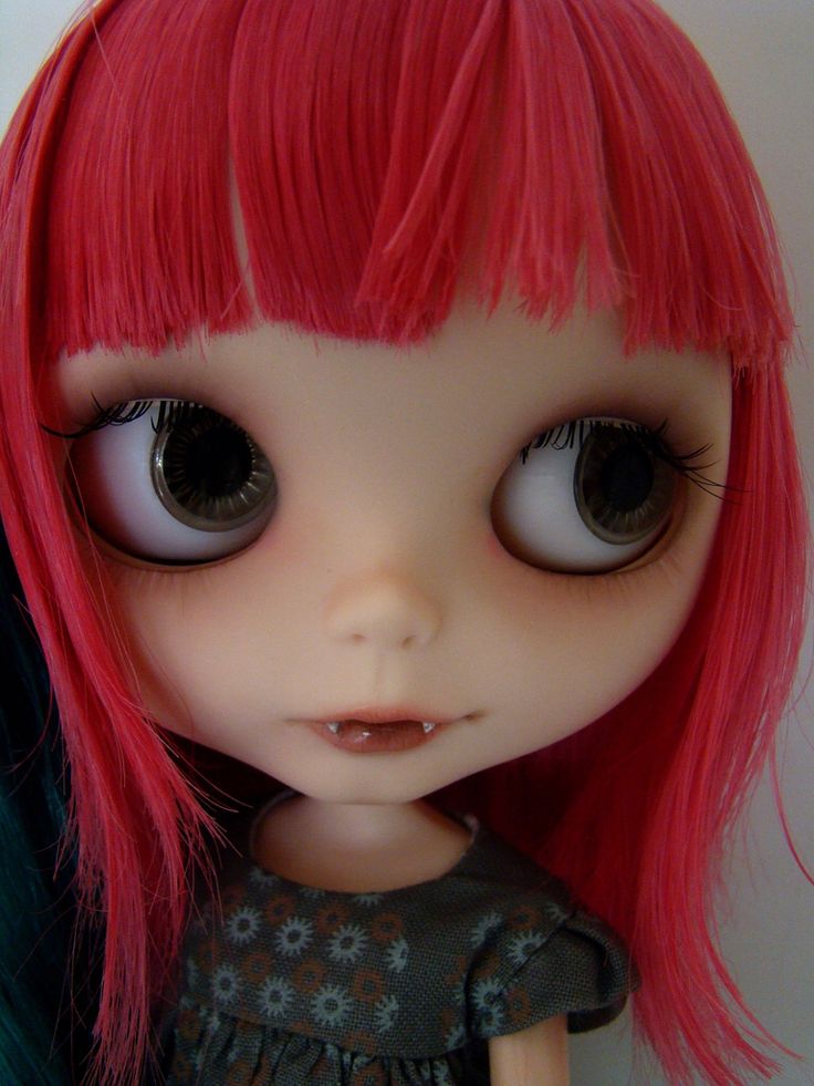 a close up of a doll with red hair and big eyes wearing a black dress