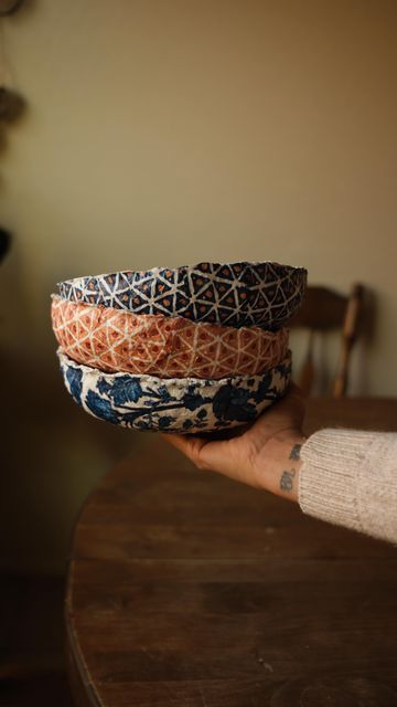 a person holding three bowls on top of a wooden table