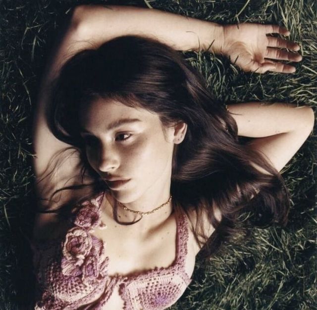 a woman laying in the grass with her hands behind her head