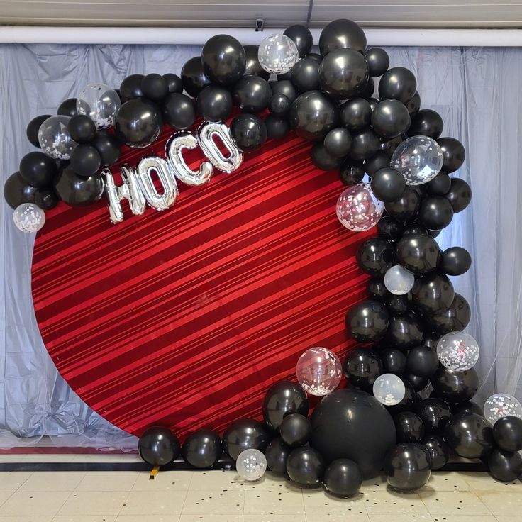 a heart shaped balloon with the word hoco on it surrounded by black and silver balloons