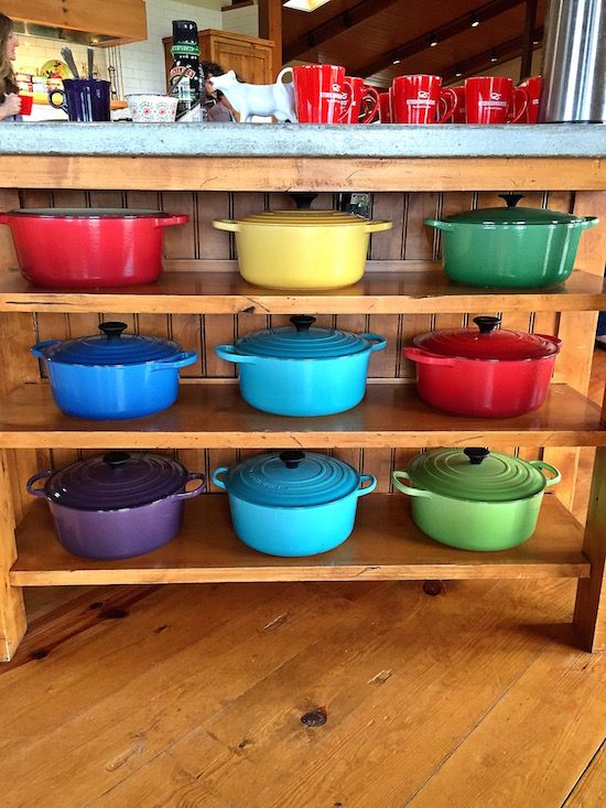 many pots and pans are stacked up on a shelf in front of the counter