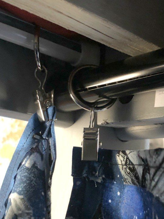 a pair of jeans hanging from the side of a window with a metal hook attached to it