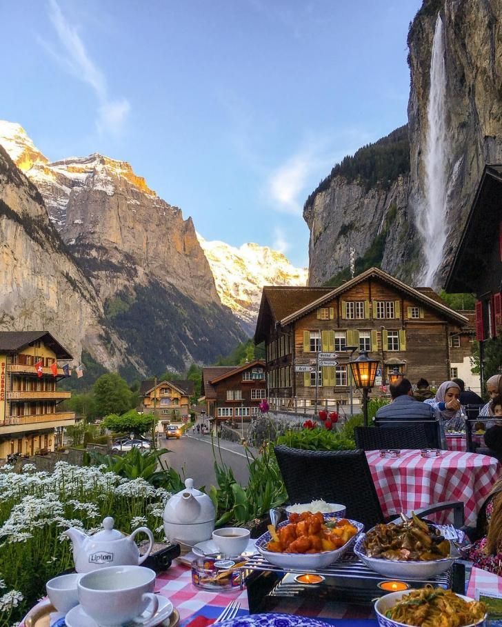 a table with food and drinks on it in the middle of a mountain village surrounded by mountains