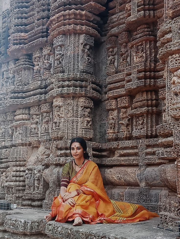 a woman is sitting on the steps in front of an intricately carved stone structure