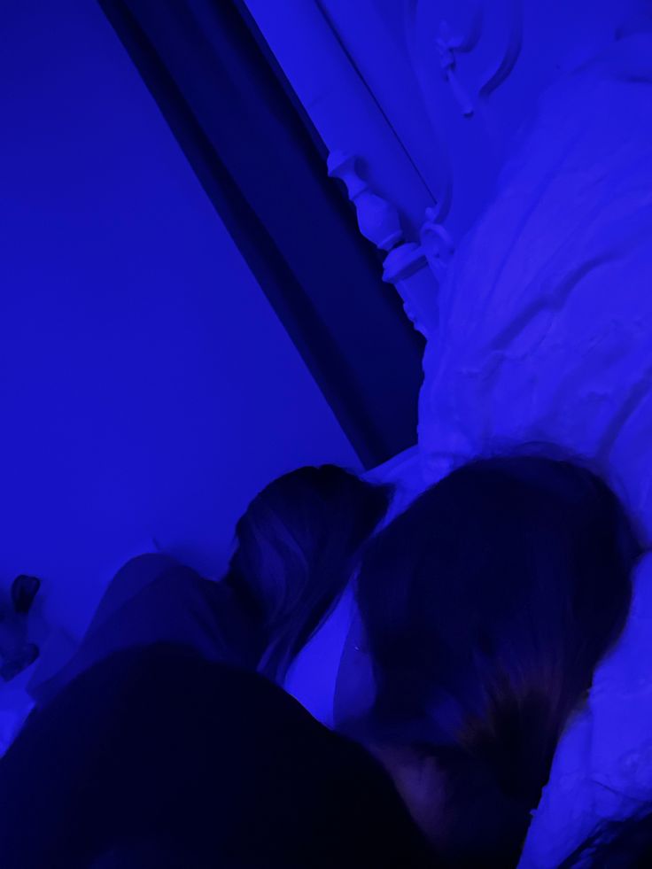 a person laying in bed with their head on the pillow and looking at something blue