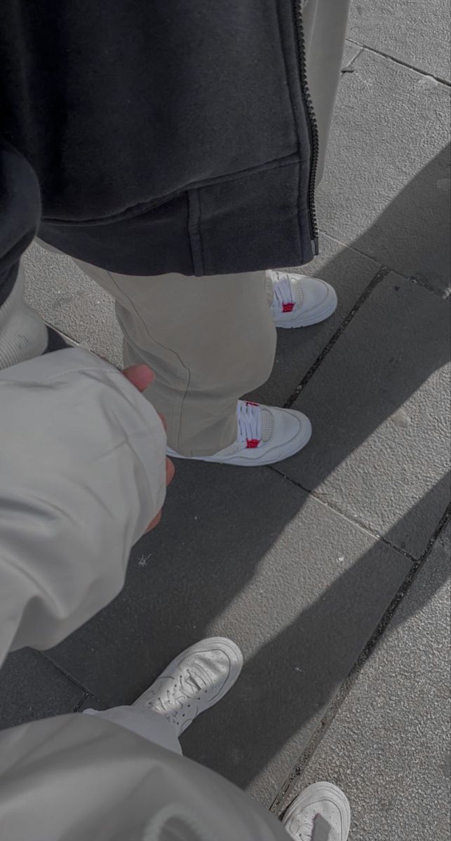 two people standing next to each other on a sidewalk with their shoes off the ground