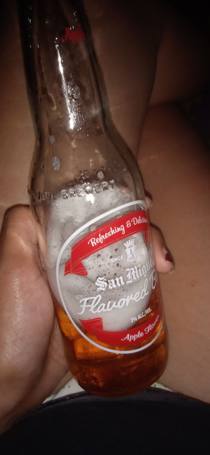 a person holding a beer bottle with ice in it's palm and the bottom half of their hand