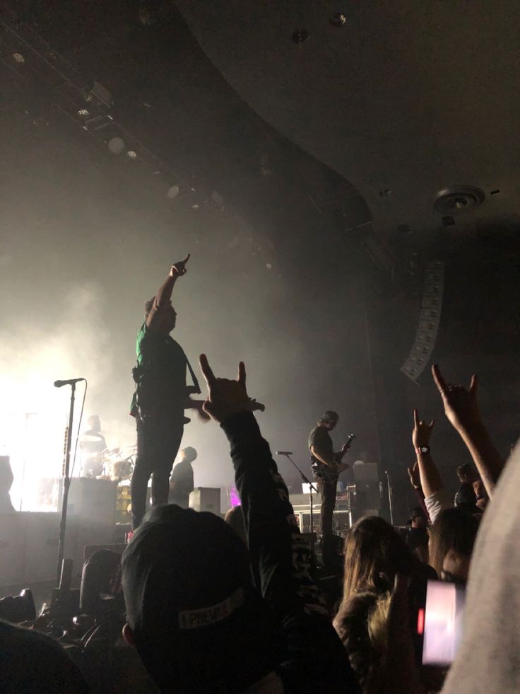 a group of people standing on top of a stage with their hands in the air