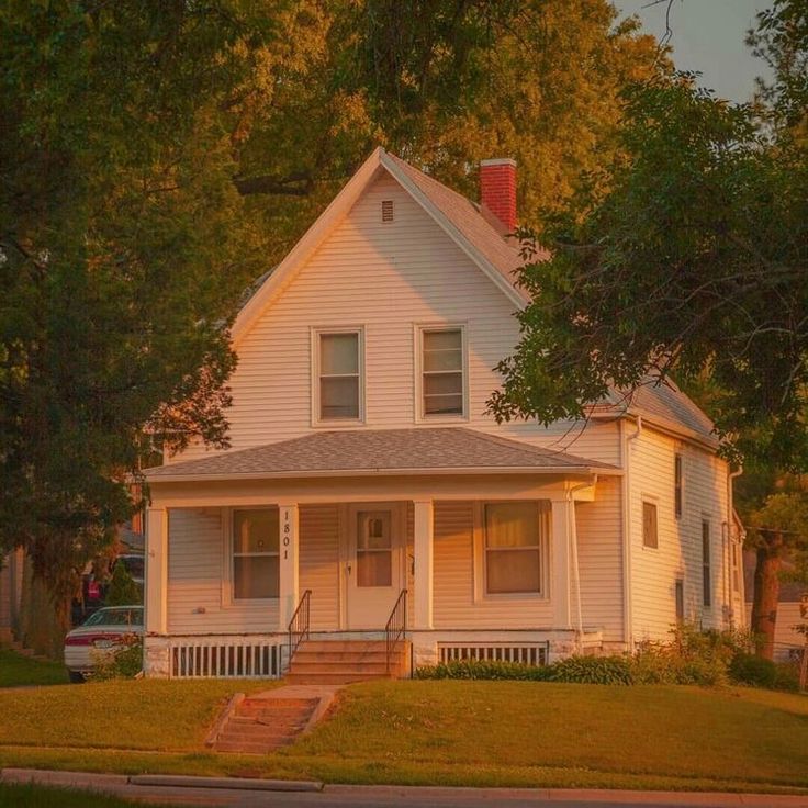 a white two story house sitting on the side of a road in front of trees