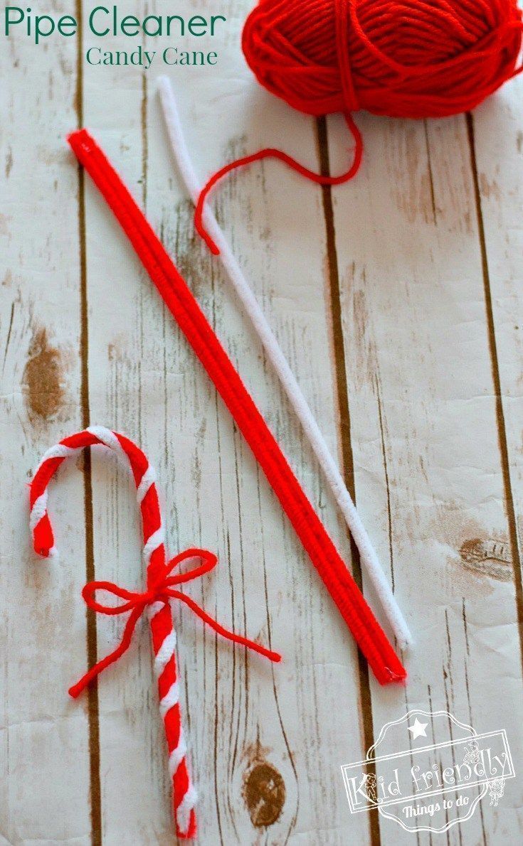 two red and white candy canes sitting on top of a wooden table next to a ball of yarn