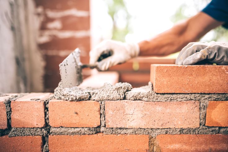 a bricklayer is working with cement on a wall