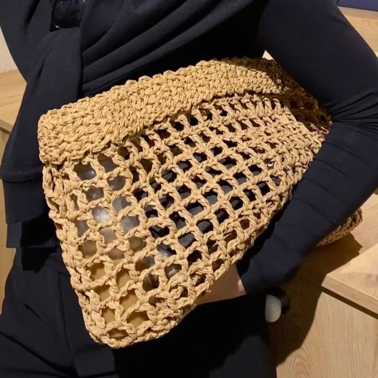 a woman is holding a crocheted purse