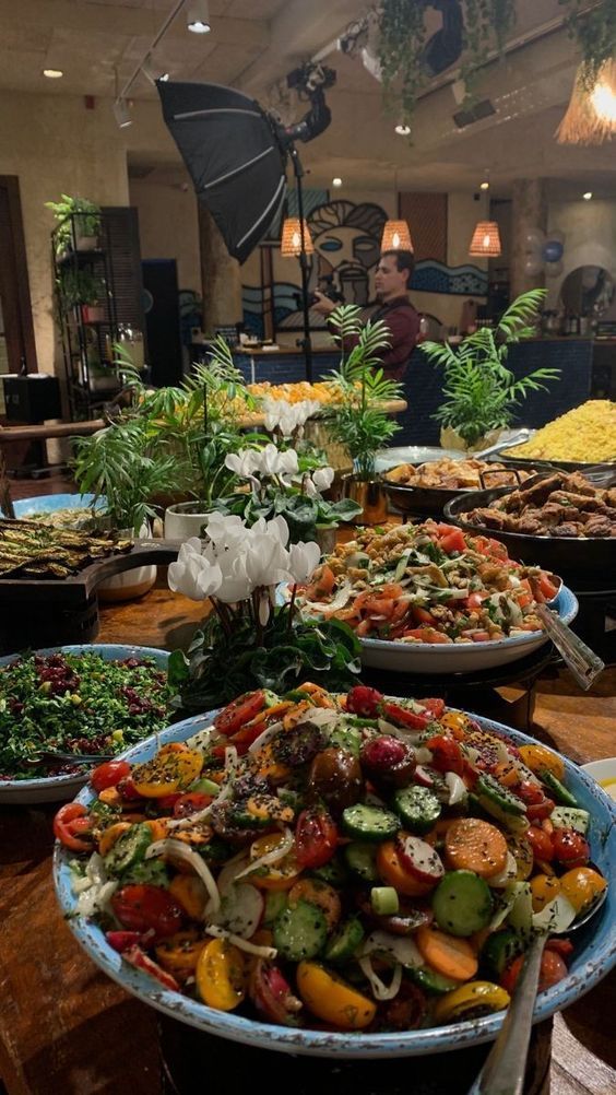 a table filled with lots of different types of food on top of wooden tables in a restaurant