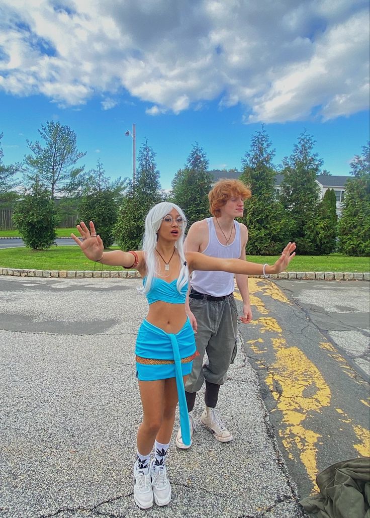 two people standing in the middle of an empty parking lot with their arms spread out