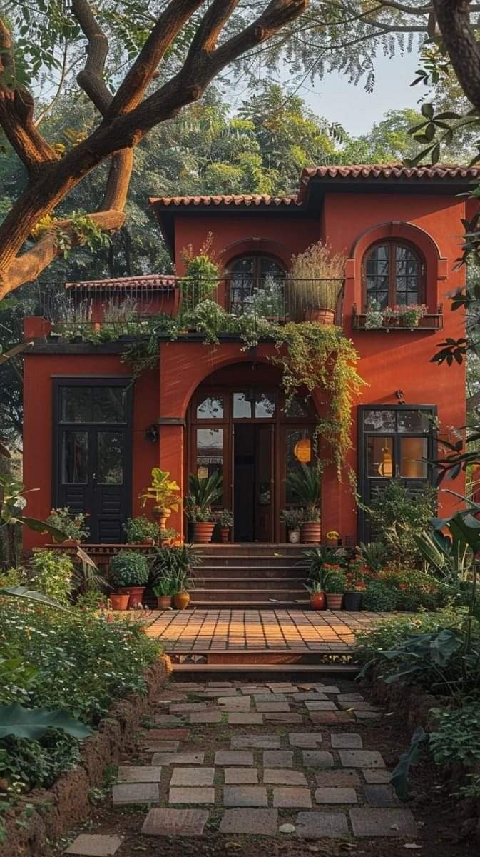 an orange house with lots of plants and trees on the front door, surrounded by greenery