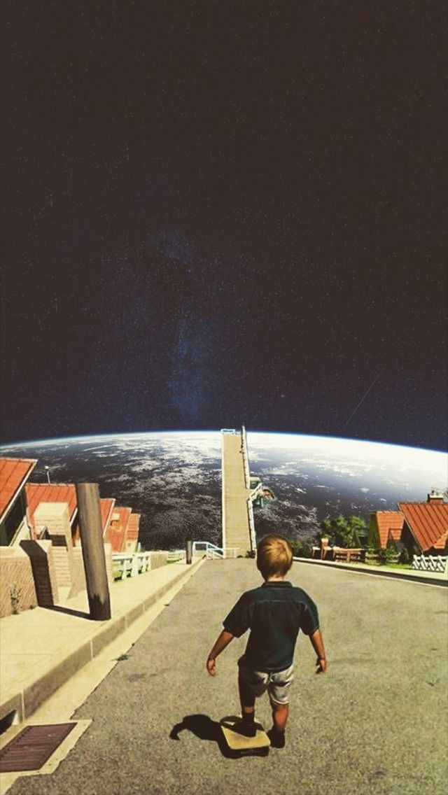 a young boy riding a skateboard down a street next to a tall building with a view of the earth in the background