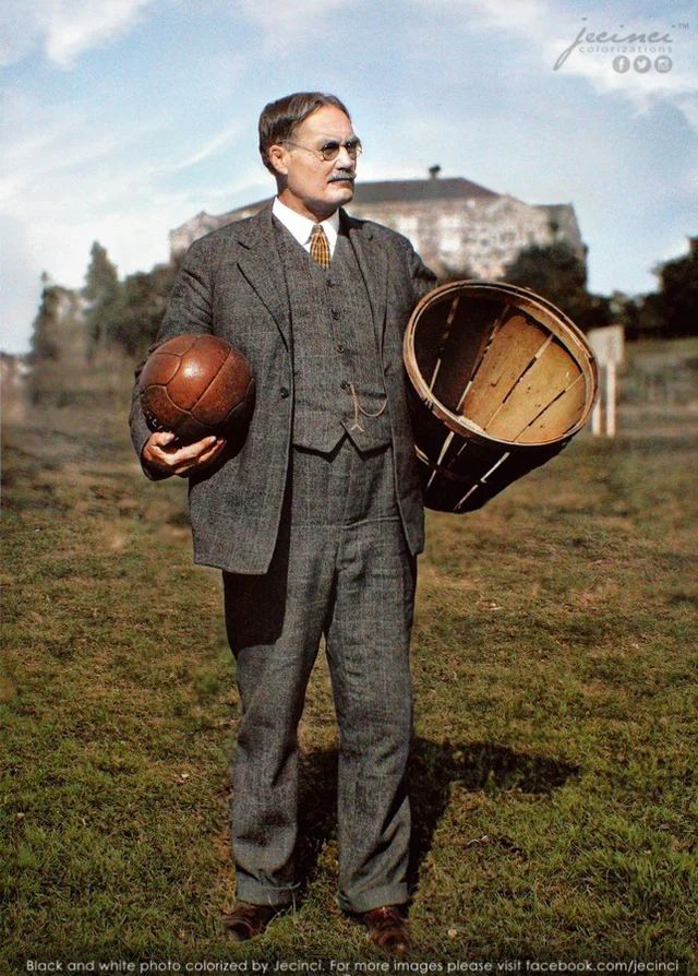 a man in a suit and tie holding a wooden barrel with a basketball inside it