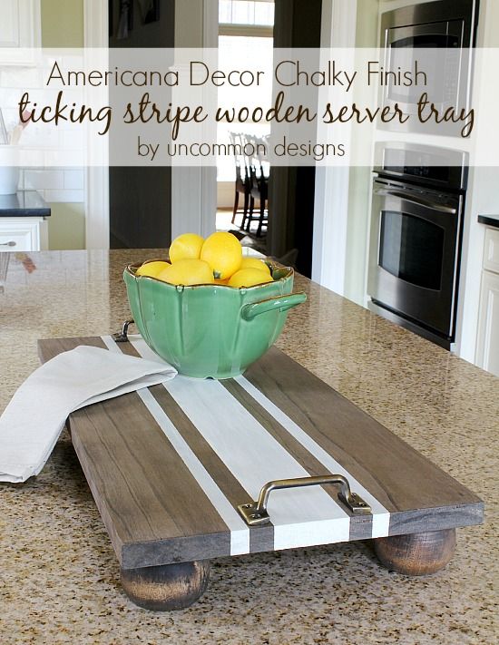 a bowl filled with lemons sitting on top of a wooden serving tray in a kitchen