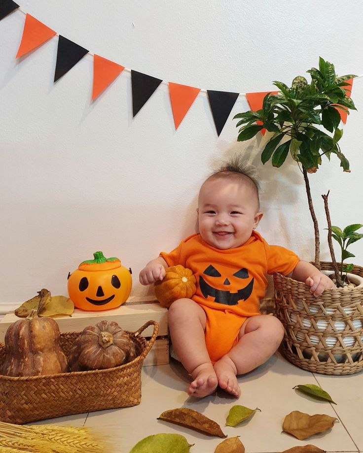 a baby sitting on the floor next to some pumpkins