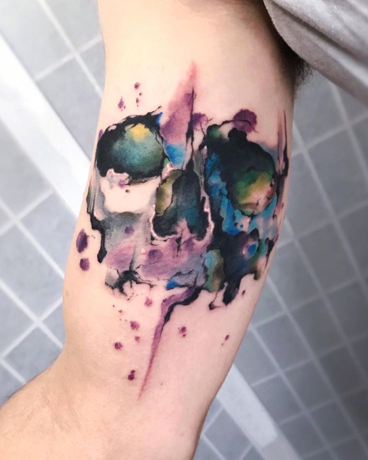 a man's arm with watercolor paint splattered on it and an abstract design