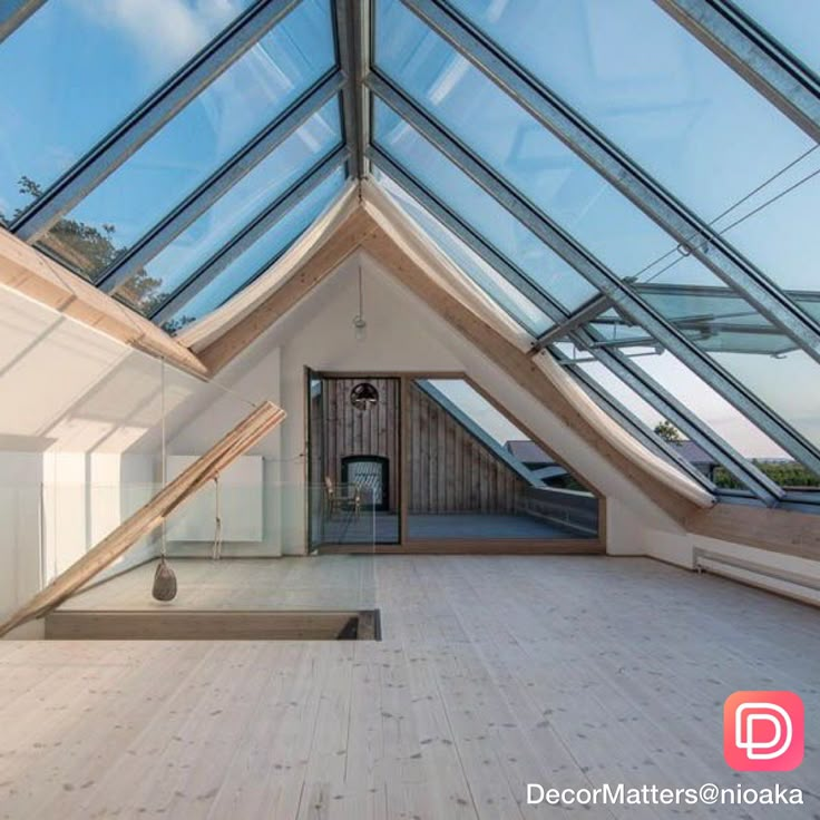 the inside of a building with glass walls and wooden flooring is seen through an opening in the roof