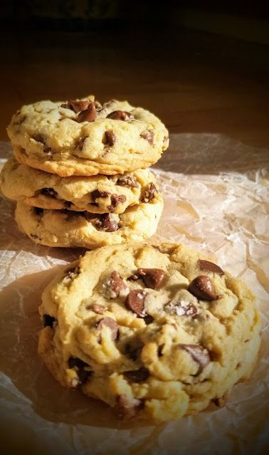 three chocolate chip cookies sitting on top of wax paper