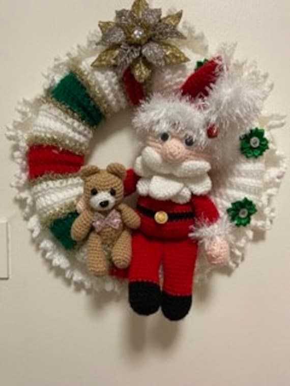 a crocheted christmas wreath with a teddy bear