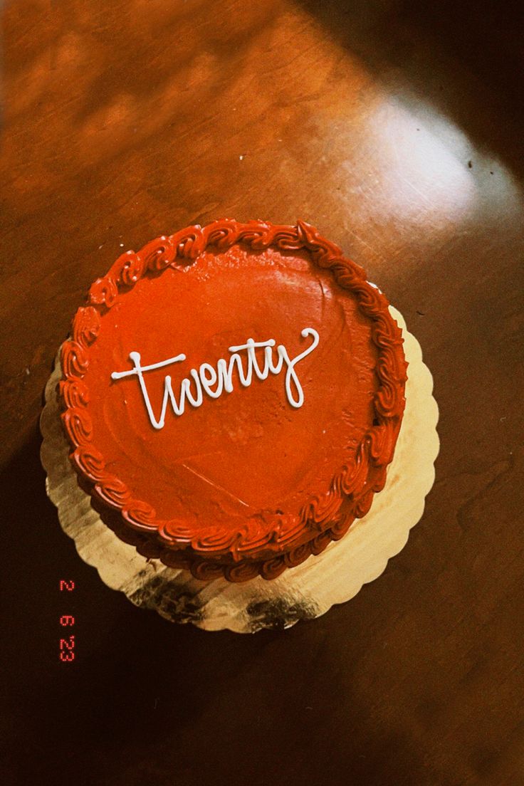 a red cake sitting on top of a table with the word twenty written on it