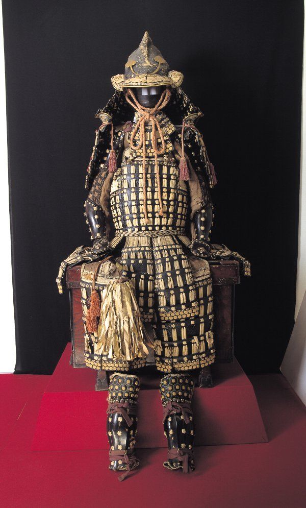 an elaborately decorated wooden statue sitting on top of a red table next to a black wall