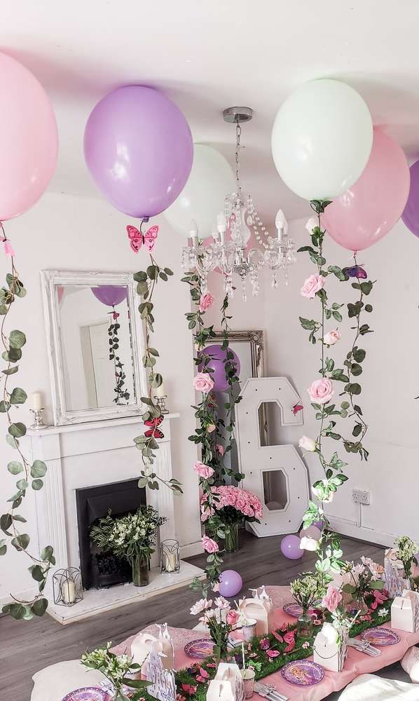 a table set up for a party with balloons and flowers