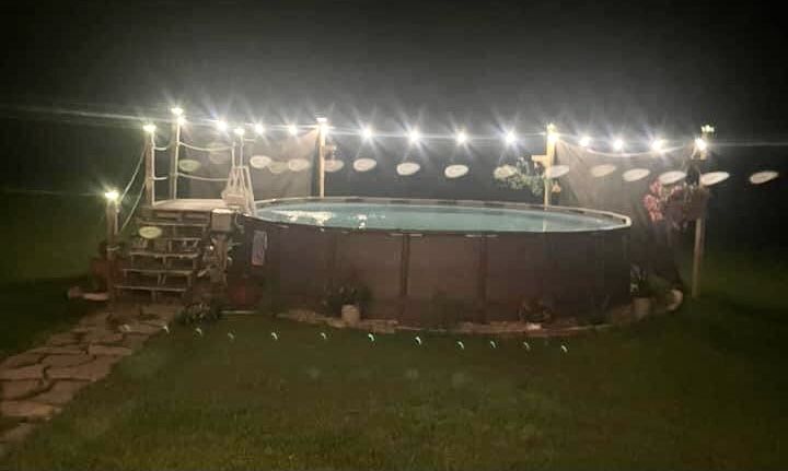 an above ground pool at night with lights on