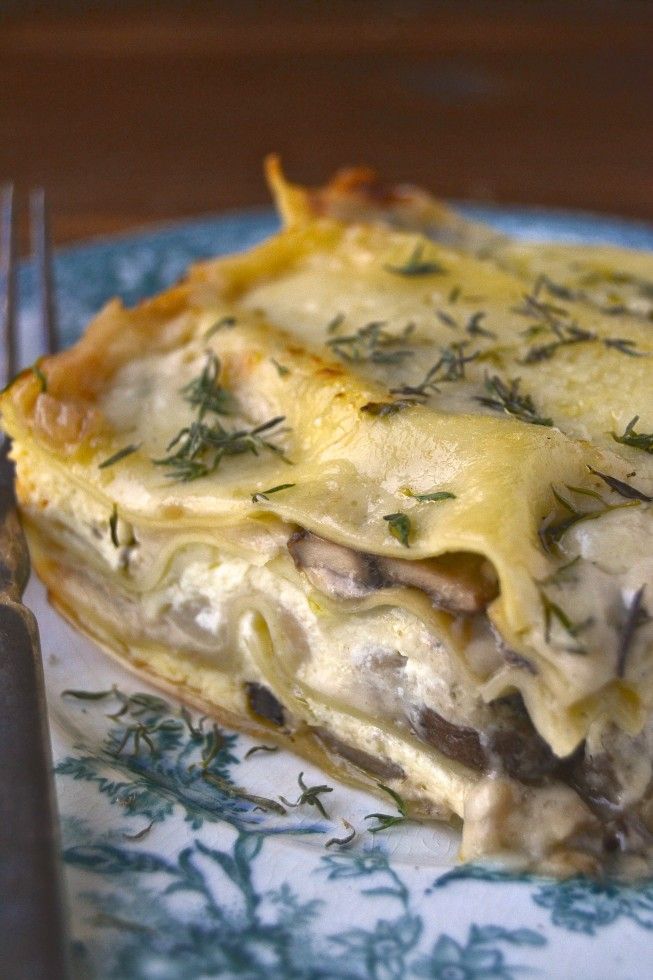 a piece of lasagna on a blue and white plate with a fork next to it