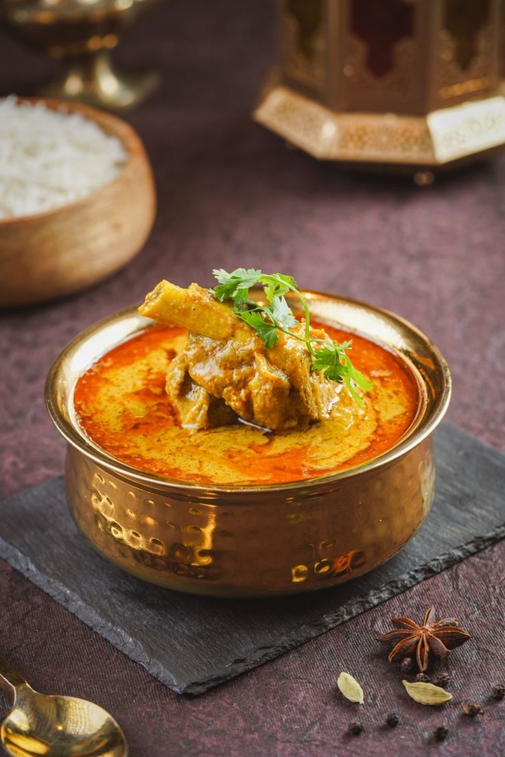 a close up of a bowl of food with rice and garnishes on the side