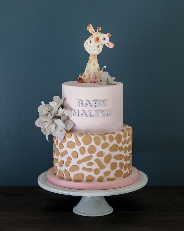 a baby giraffe themed cake with flowers on the top and bottom tiers