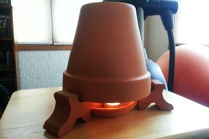 a lamp sitting on top of a wooden table next to a book shelf and window