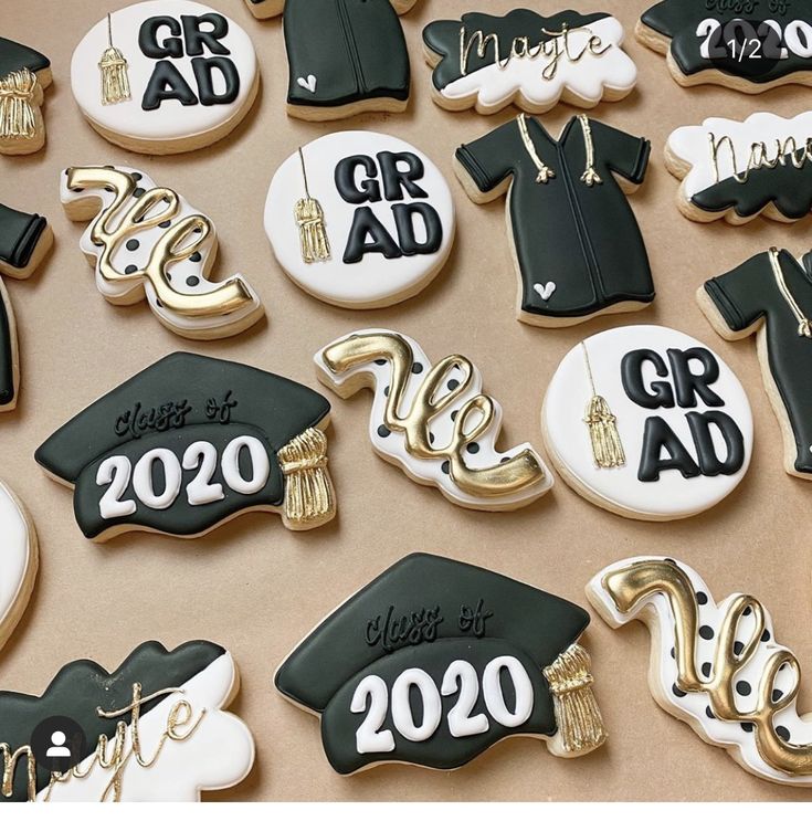 graduation cookies decorated in black and white with gold trimmings are arranged on a table