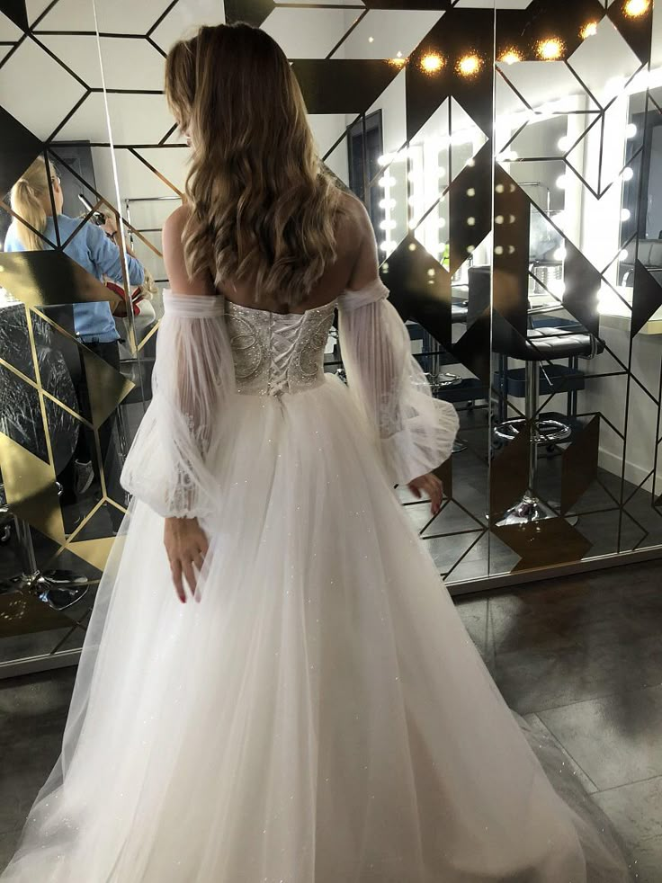 a woman in a white wedding dress looking at herself in the mirror with her reflection