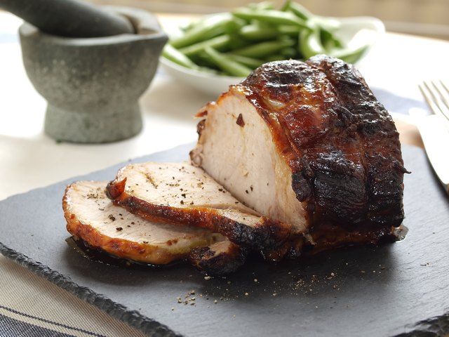 sliced pork on a slate platter with fork and knife