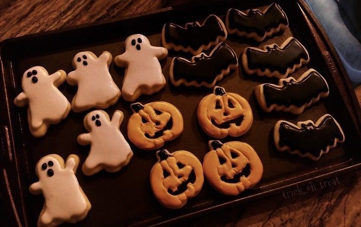 there are many decorated cookies in the tray on the table, including ghost and pumpkins