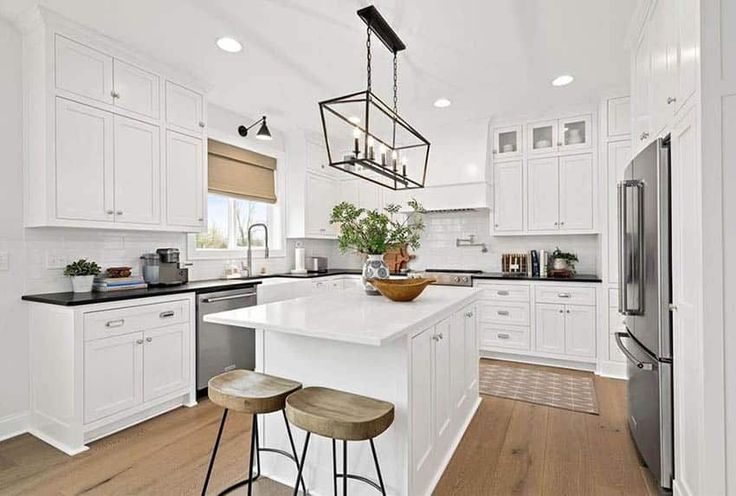 a kitchen with white cabinets and an island in the middle, surrounded by stools