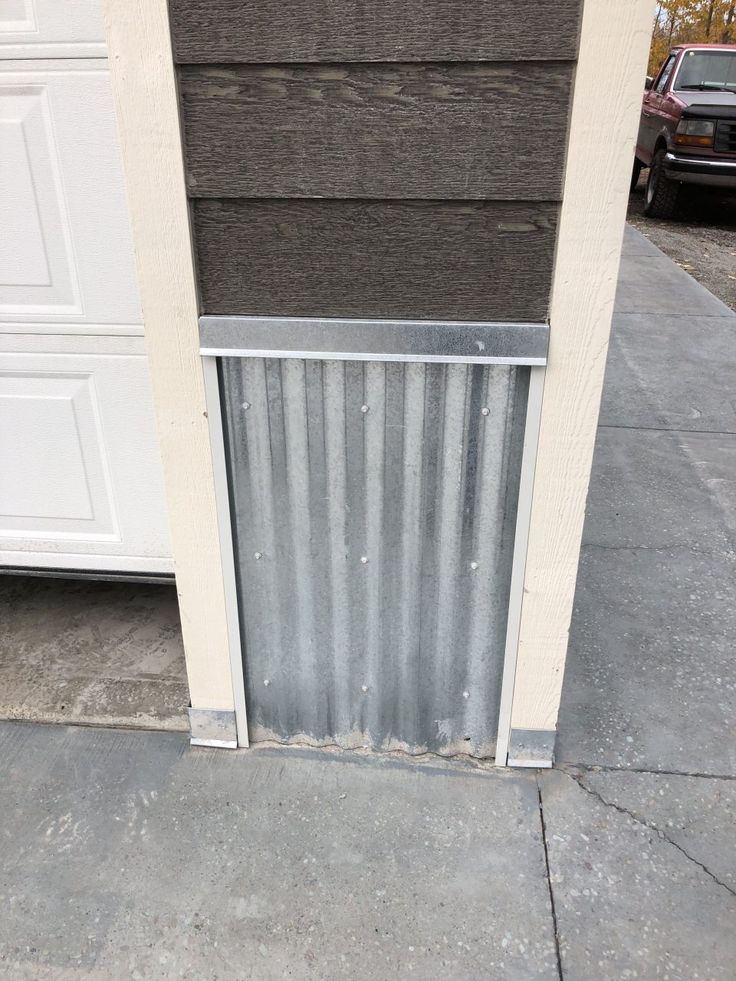 the side of a building with a metal door on it's side and a car parked next to it