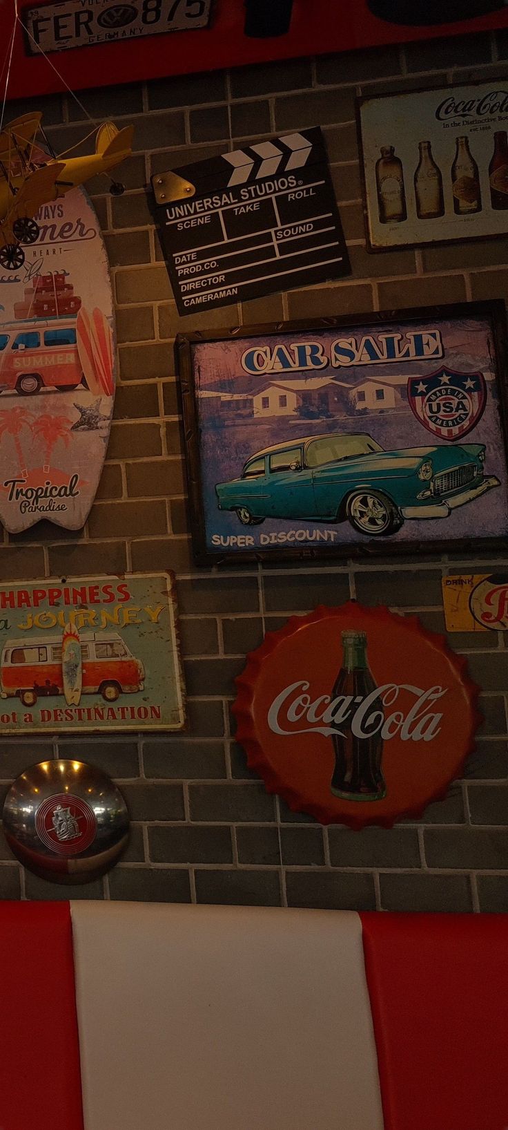 several signs are hanging on the wall above a red counter top and below it is a coca - cola sign