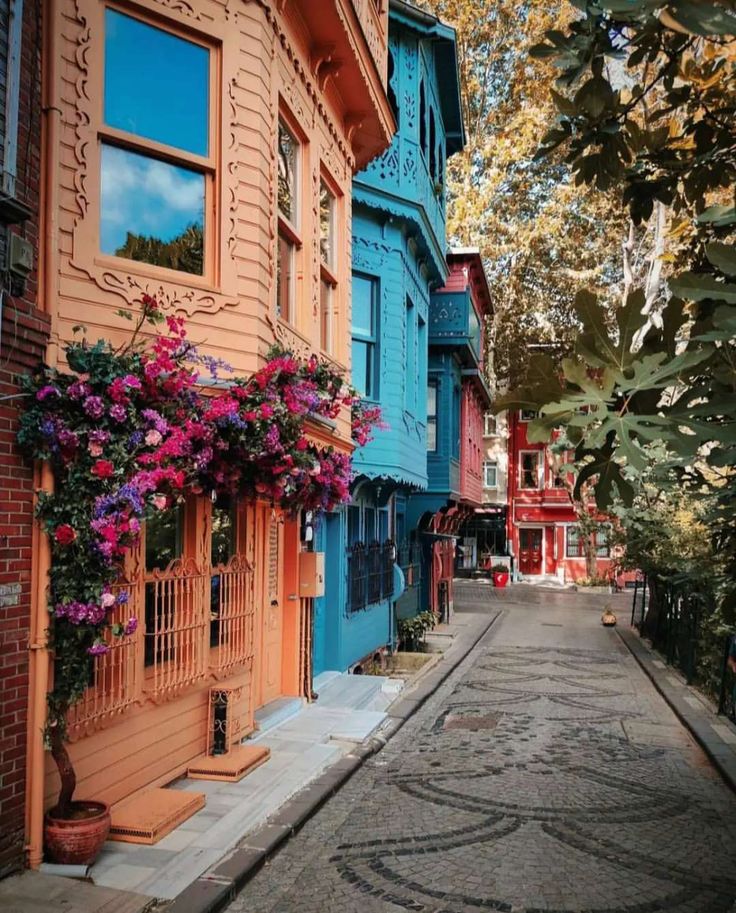 an alleyway with colorful buildings and flowers on the window boxes in front of them