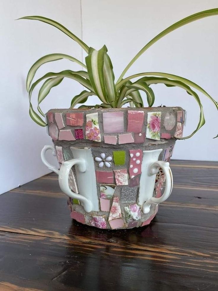 there is a plant in the cup that has been made out of tiles and flowers