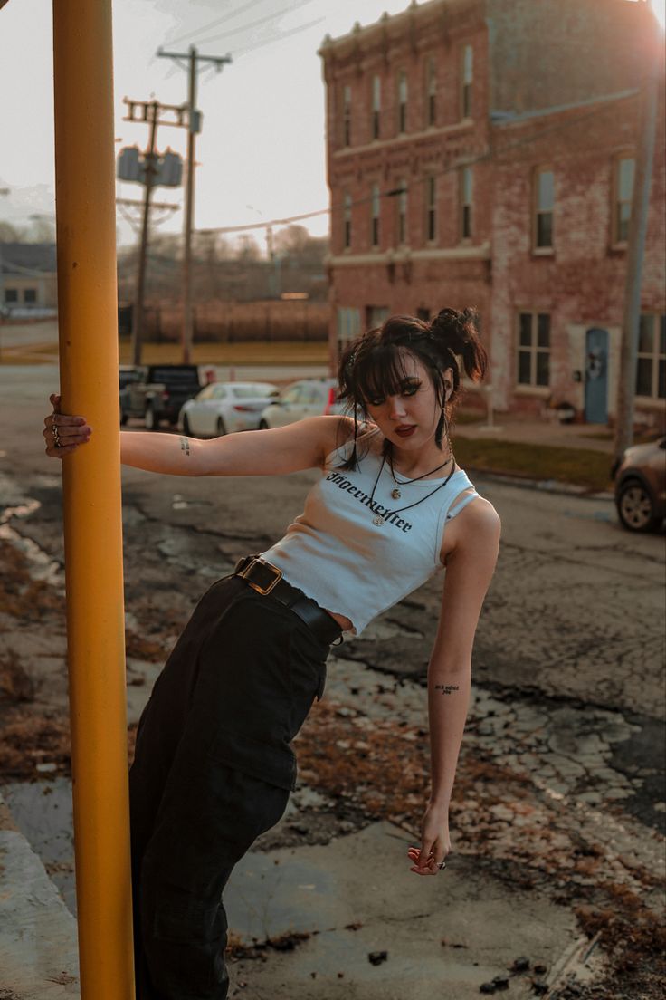 a woman leaning up against a pole on the street